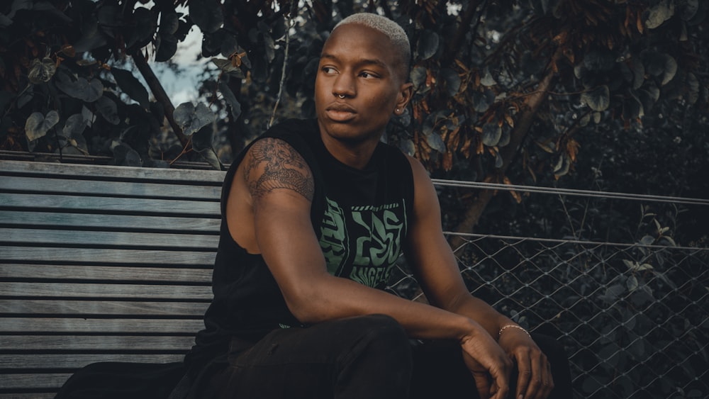 man in black tank top sitting on bench