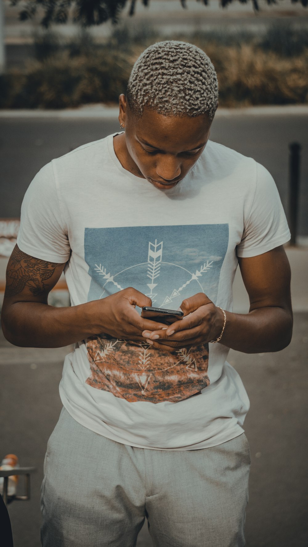 黒いスマートフォンを持つ白いクルーネックTシャツの男