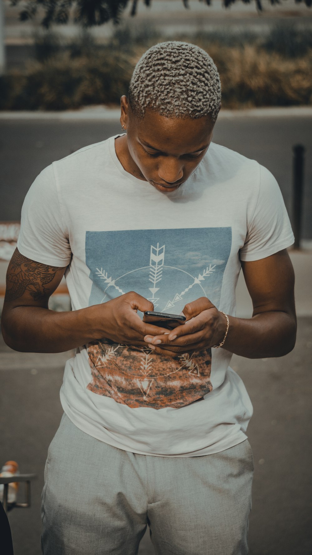 man in white crew neck t-shirt holding black smartphone
