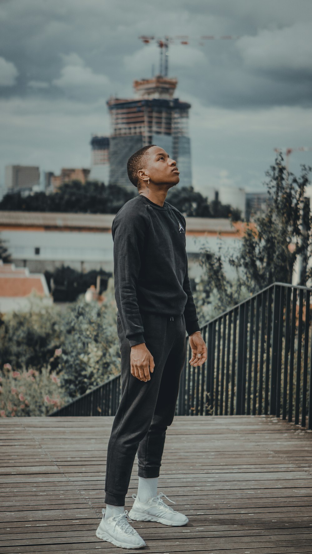 man in black dress shirt and black pants standing on brown wooden bridge during daytime