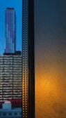 Evening cityscape viewed from the office window with purple lighting inside.