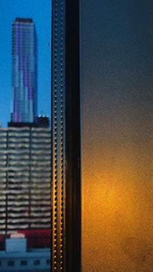 Evening cityscape viewed from the office window with purple lighting inside.