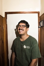 man in green crew neck t-shirt wearing black framed eyeglasses