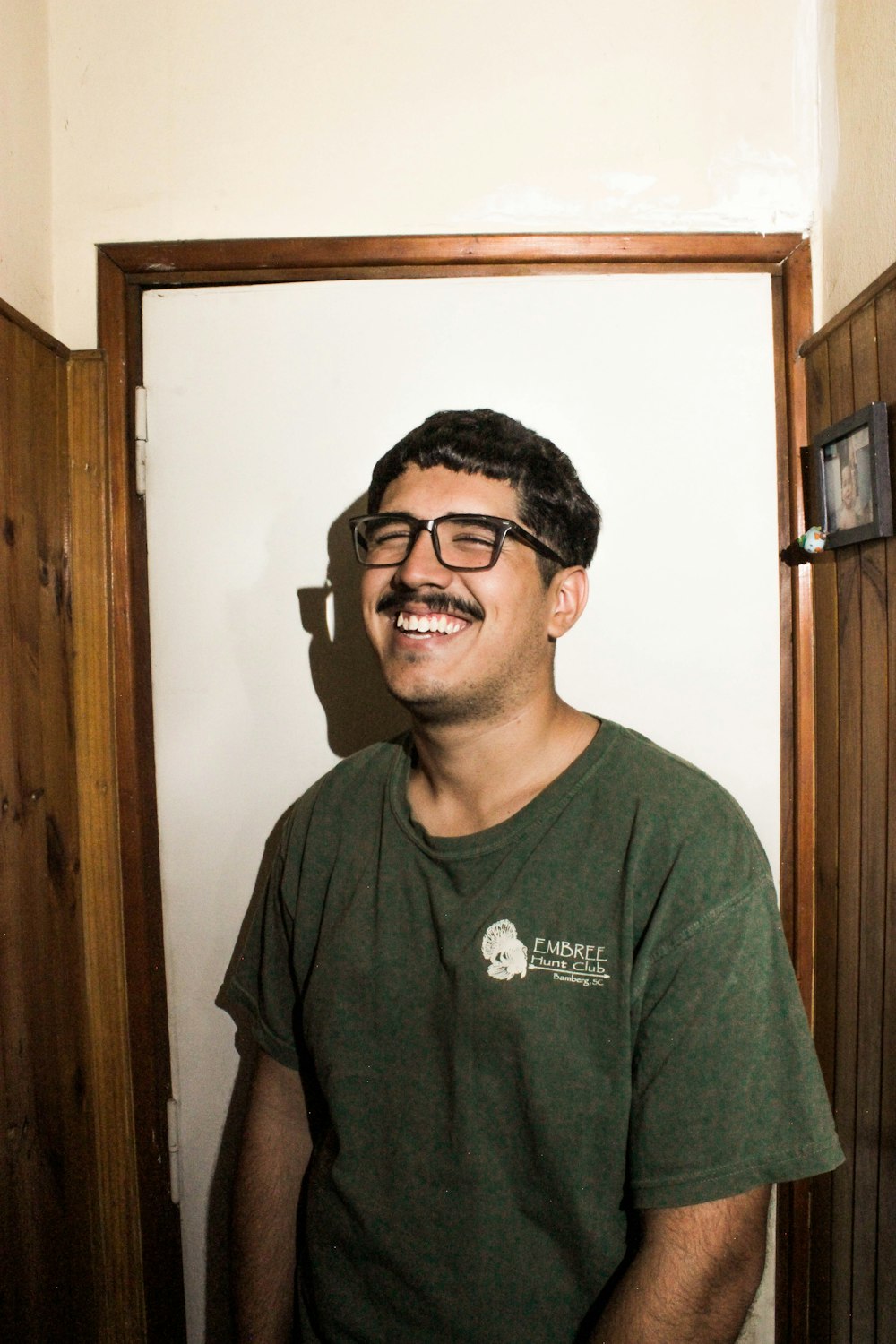man in green crew neck t-shirt wearing black framed eyeglasses