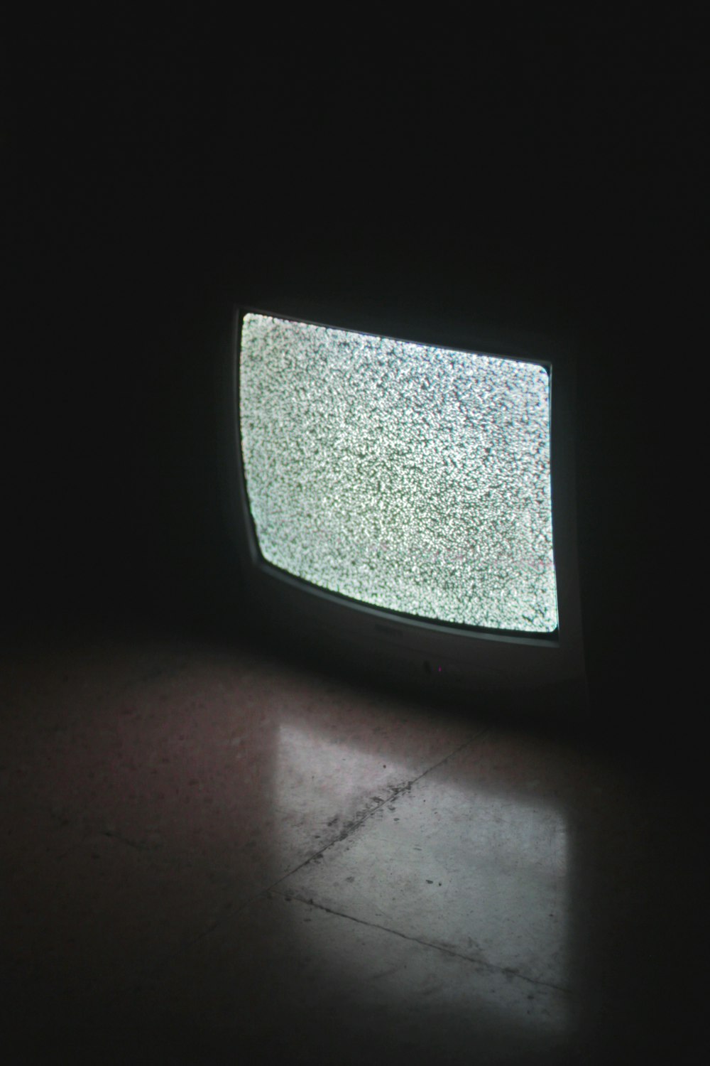tv crt cinza ligado em um quarto escuro