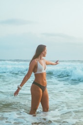 woman in black bikini standing on sea water during daytime
