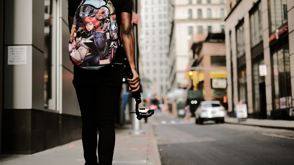 woman in black and red skull print t-shirt and black pants holding black dslr camera
