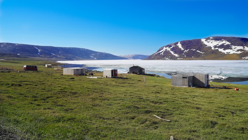 Maison blanche et brune près du champ d’herbe verte et de la montagne sous le ciel bleu pendant la journée