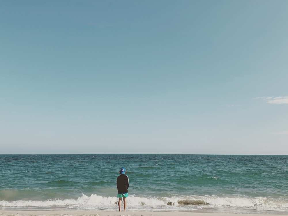 woman in black shirt and pink pants standing on beach during daytime