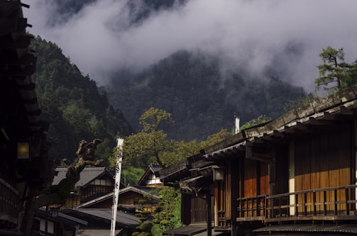 A serene Japanese village with traditional houses surrounded by lush greenery during autumn.