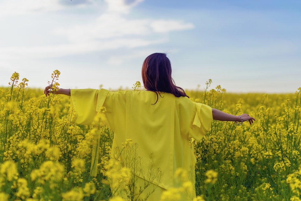 woman in yellow shirt standing on yellow flower field during daytime