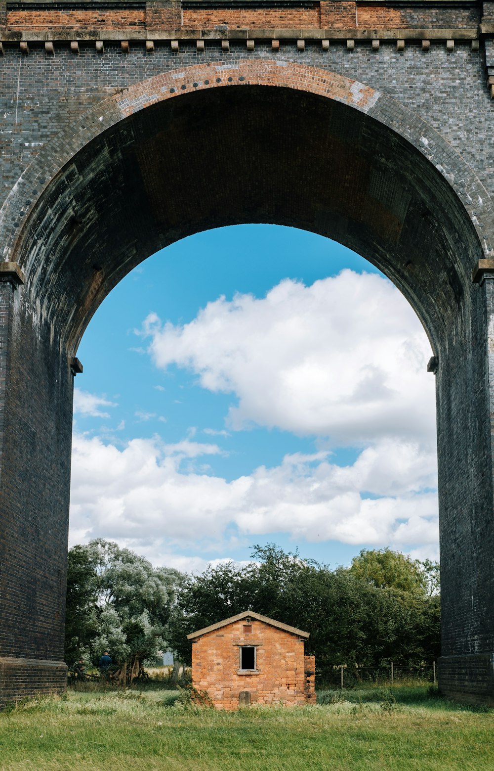 Arco de hormigón marrón bajo el cielo azul durante el día