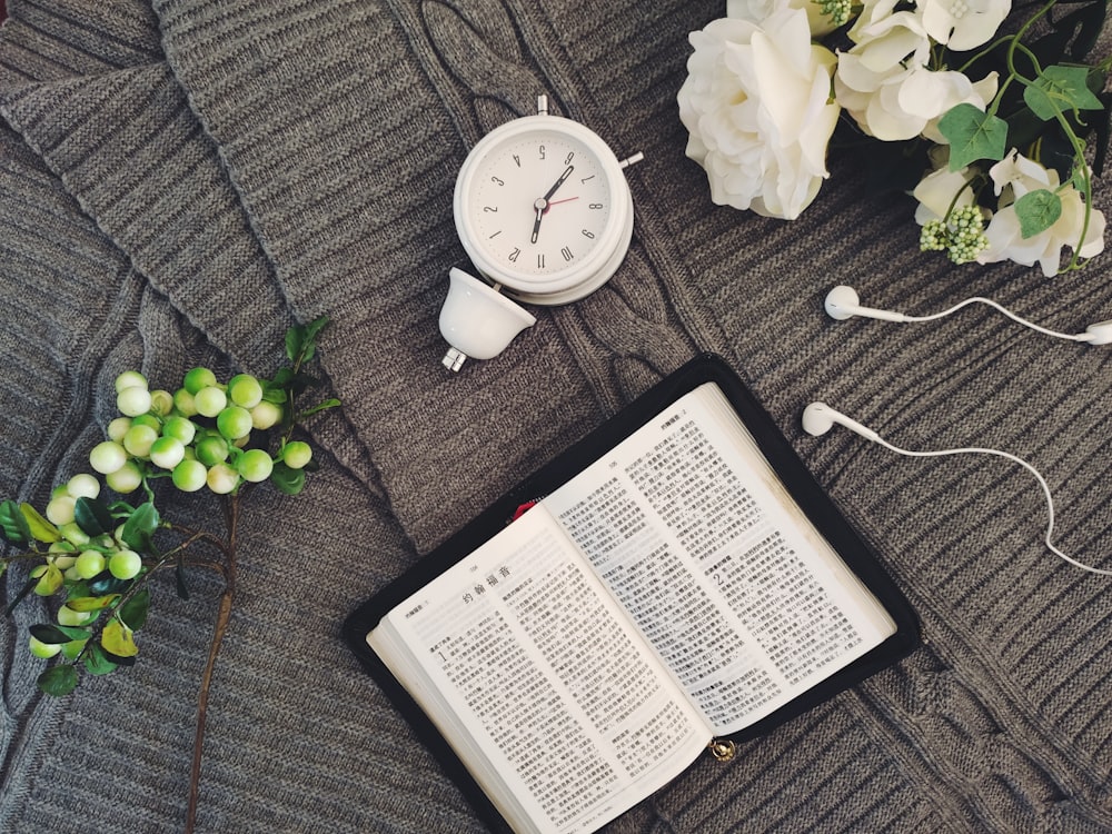 white book beside white round analog wall clock