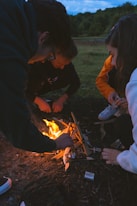 man in black jacket holding burning charcoal