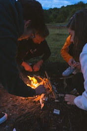 man in black jacket holding burning charcoal