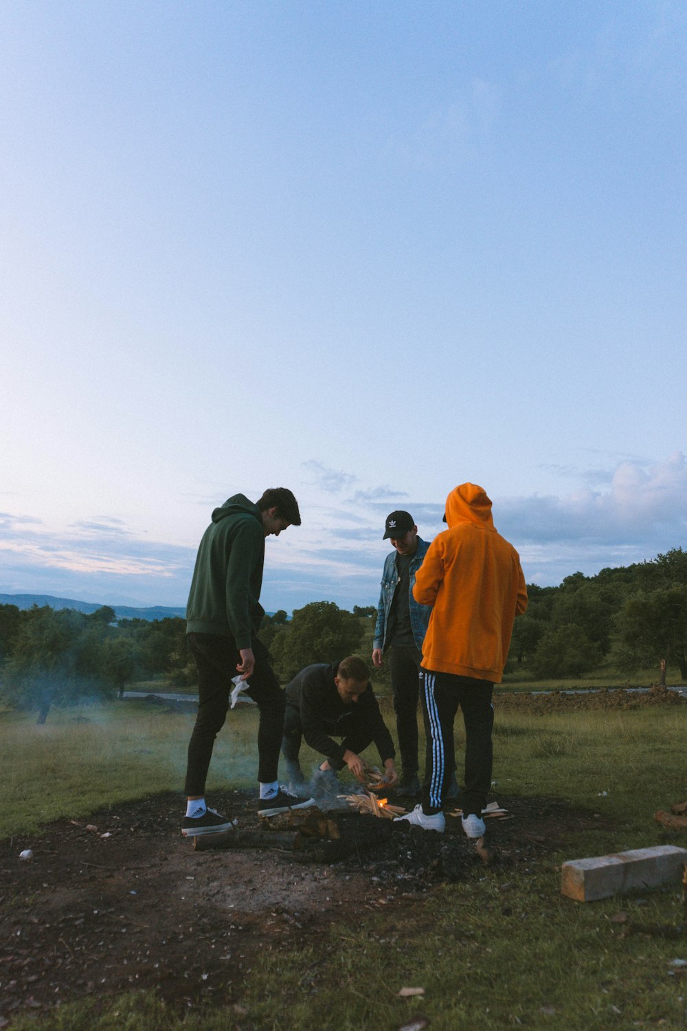 man in black jacket standing beside man in orange hoodie