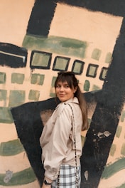 girl in white button up shirt and black vest standing beside wall