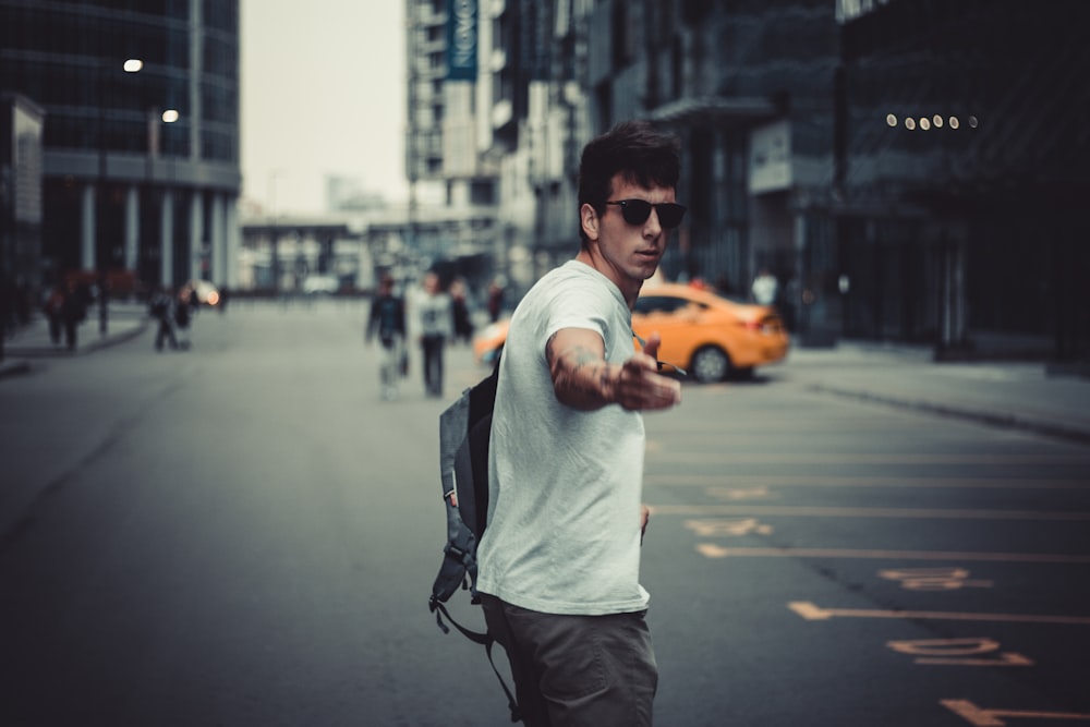 man in white shirt and black pants standing on road during daytime