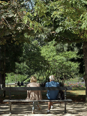 An elderly couple smiling together on a park bench, enjoying their retirement.
