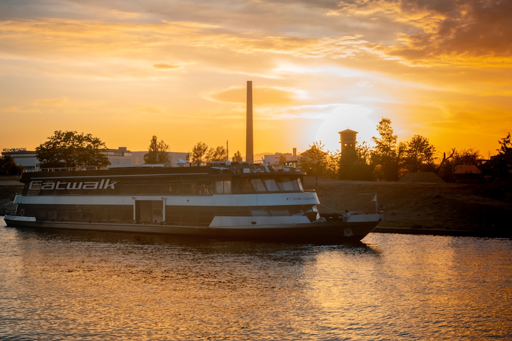 white and black boat on body of water during sunset