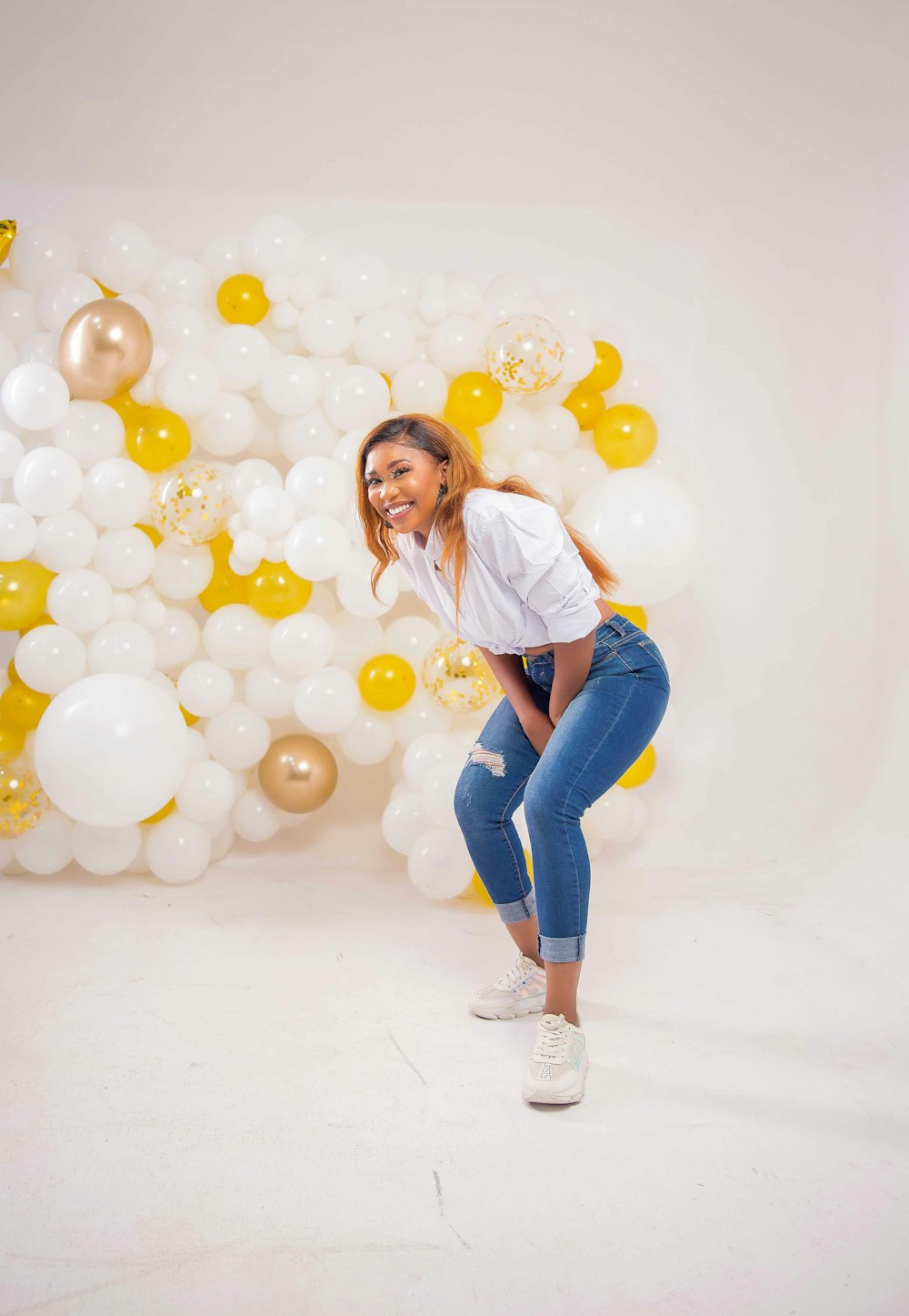 woman in white long sleeve shirt and blue denim jeans standing on white balloons