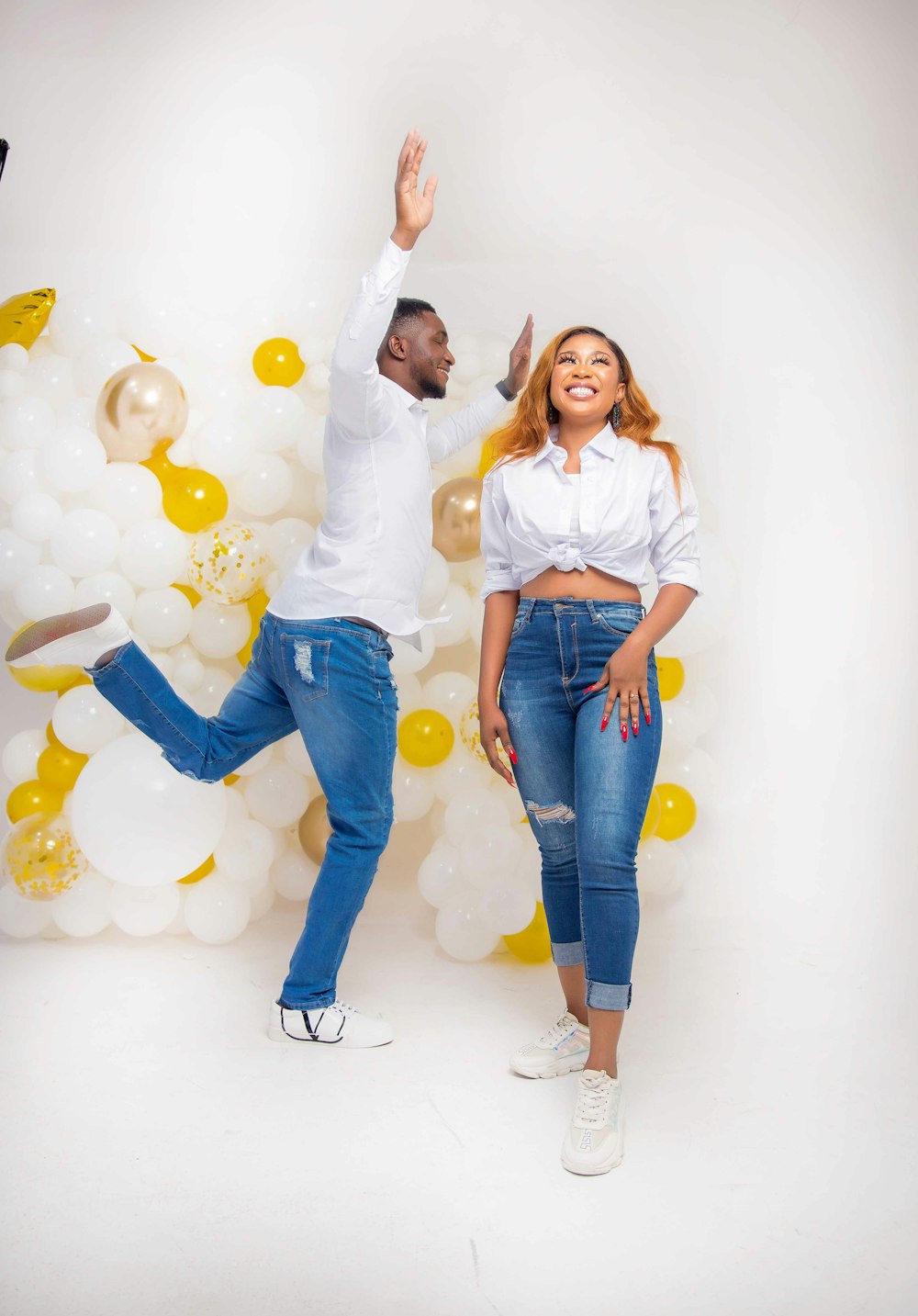 girl in white long sleeve shirt and blue denim jeans standing beside balloons