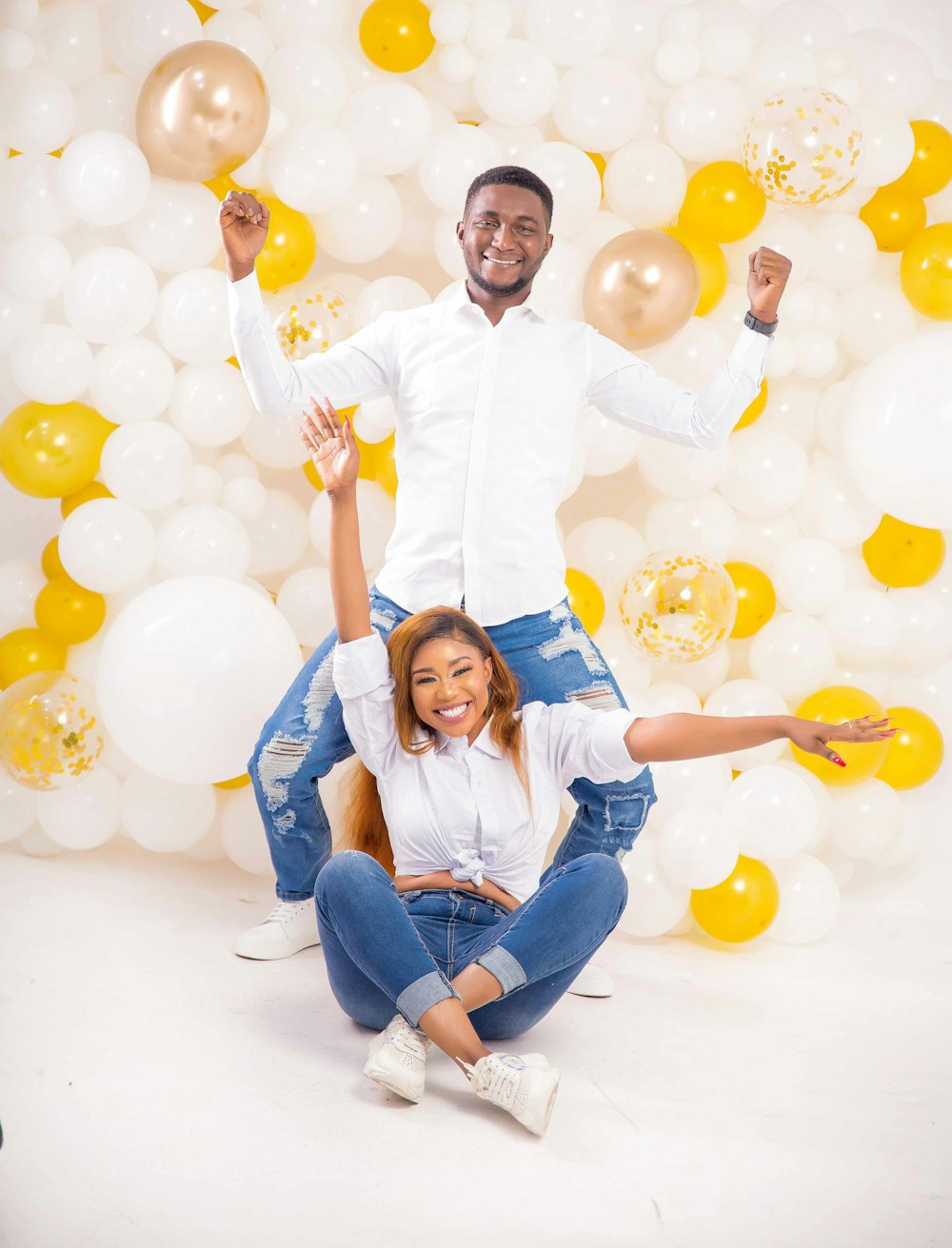 girl in white dress shirt and blue denim jeans sitting on white floor