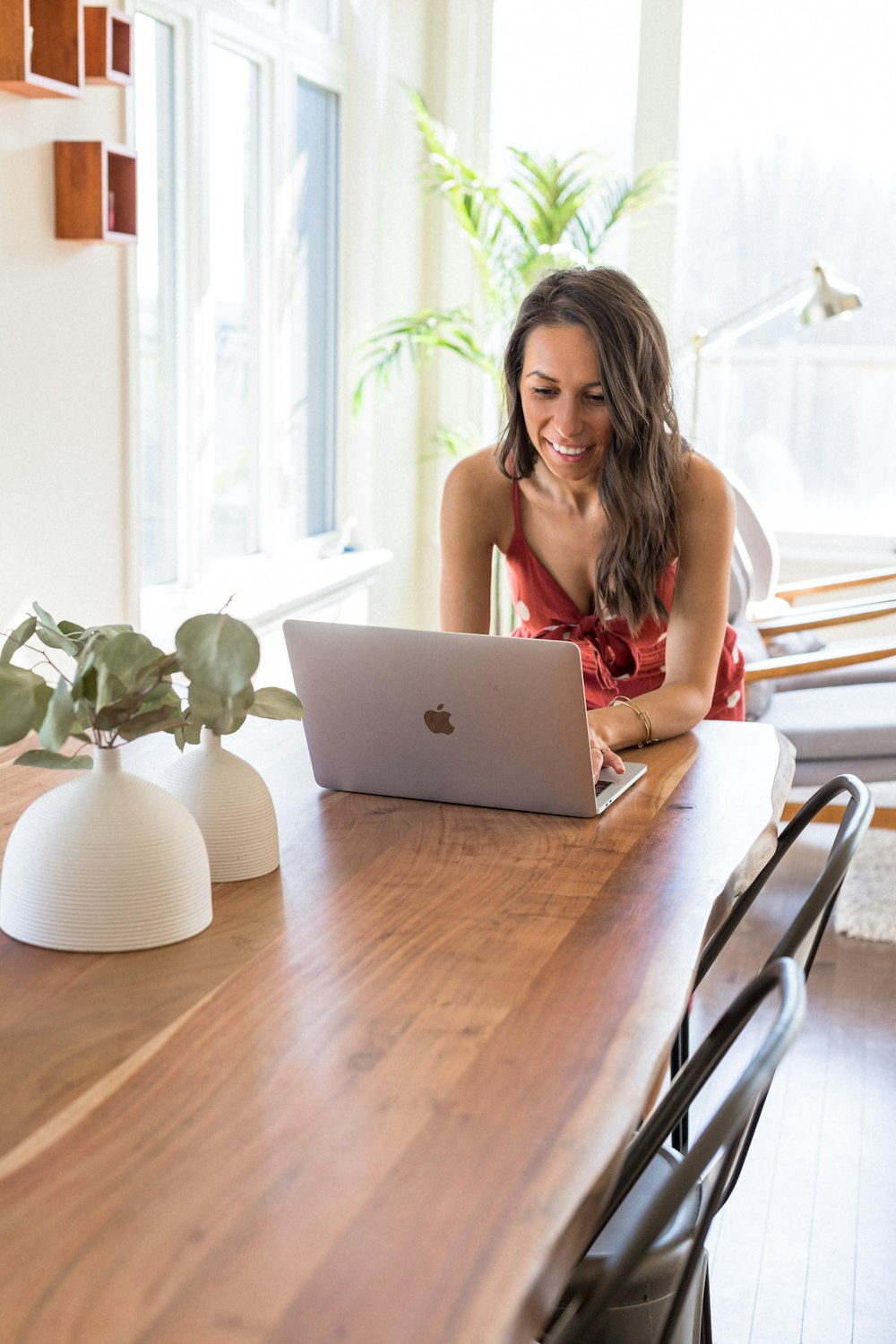 woman in red tank top sitting on chair using macbook