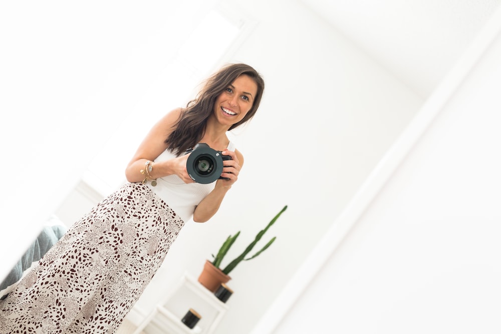 woman in white and black sleeveless dress holding black camera