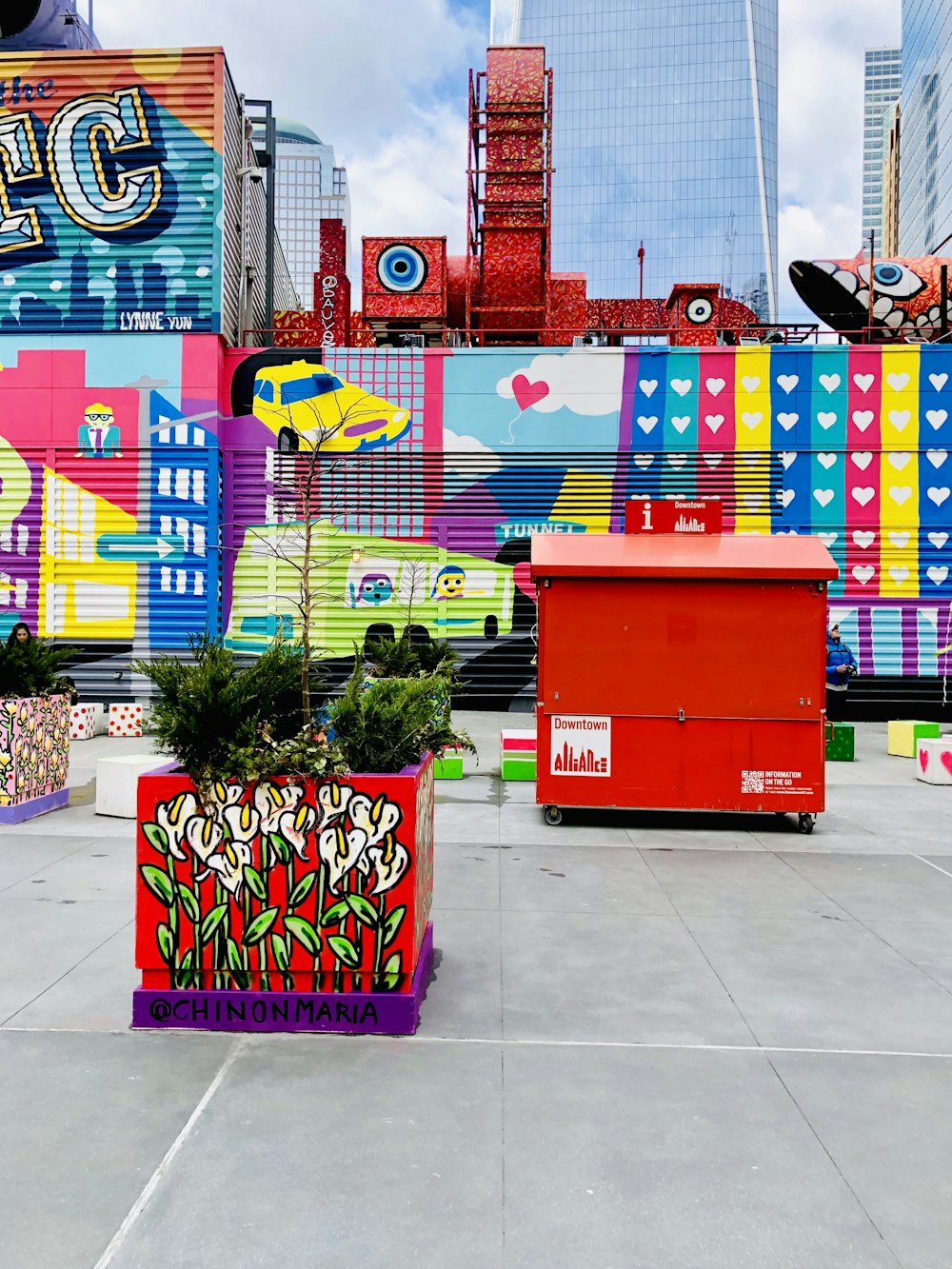 red plastic trash bin beside green potted plant