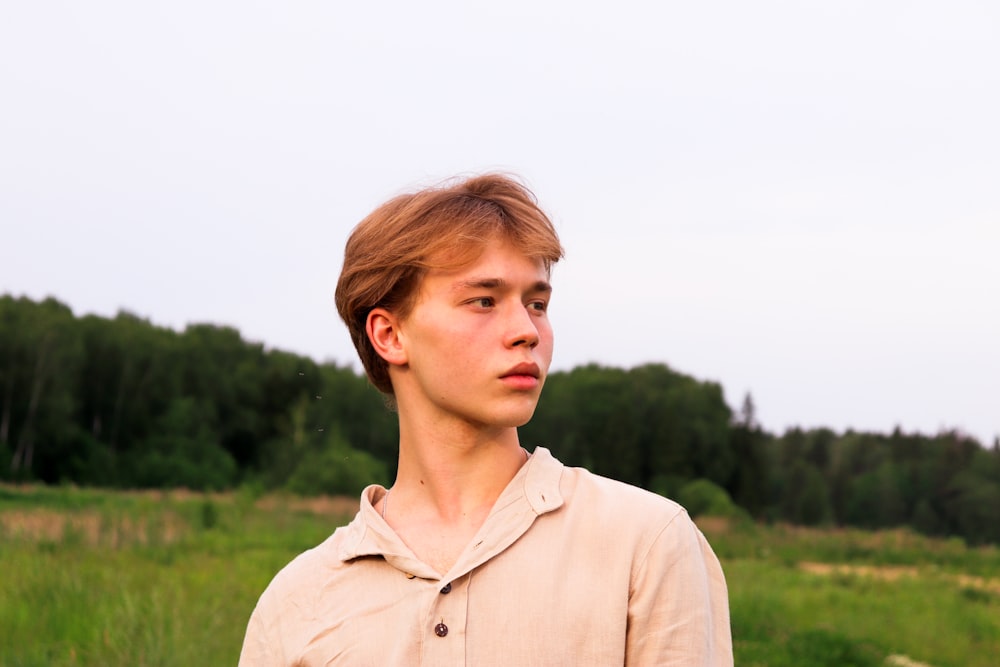 man in beige collared shirt standing on green grass field during daytime