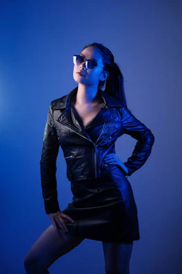 A powerful pose of a mature dominatrix wearing a tailored leather jacket, exuding authority.