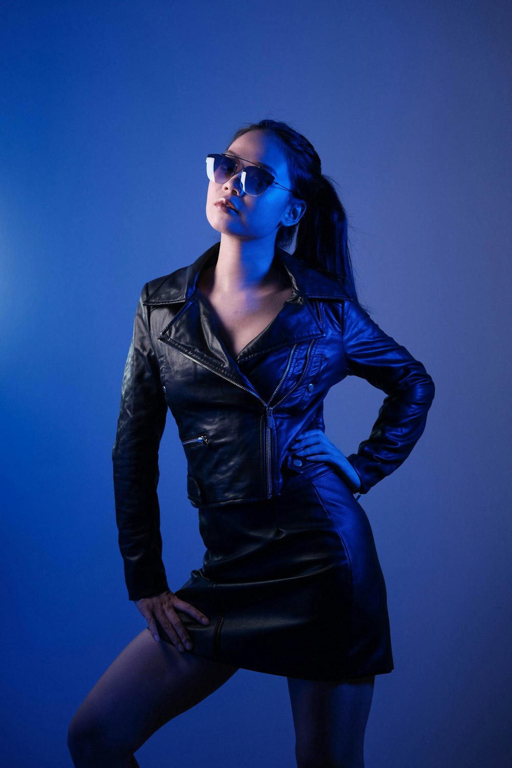 woman in black leather jacket wearing blue sunglasses