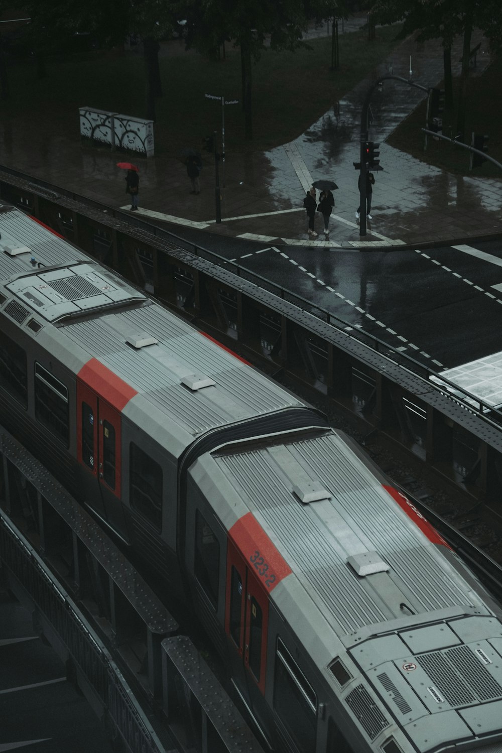 man in black jacket walking on sidewalk near red and white train