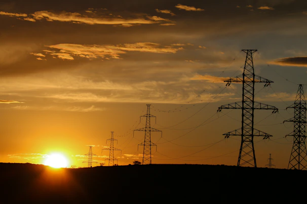 Sunset casting golden light over a solar array with silhouettes of workers maintaining the site.