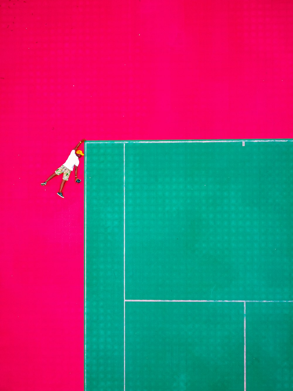 man in white shirt and black shorts jumping on green tennis court