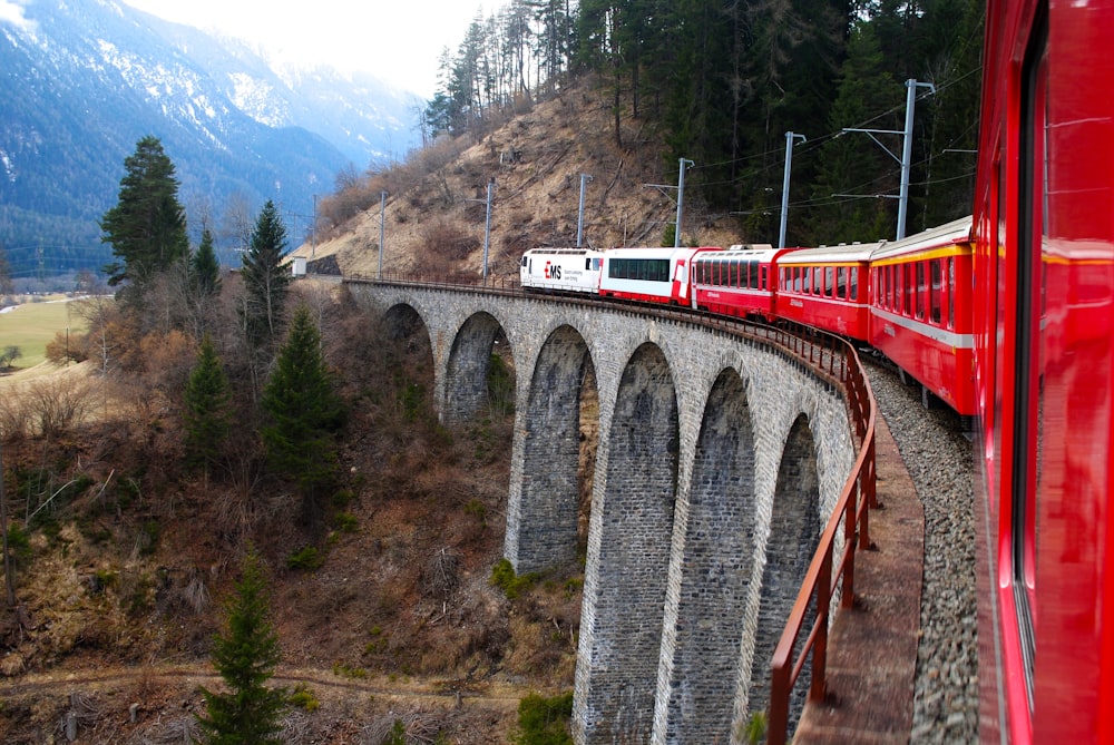 red and white train on rail bridge during daytime