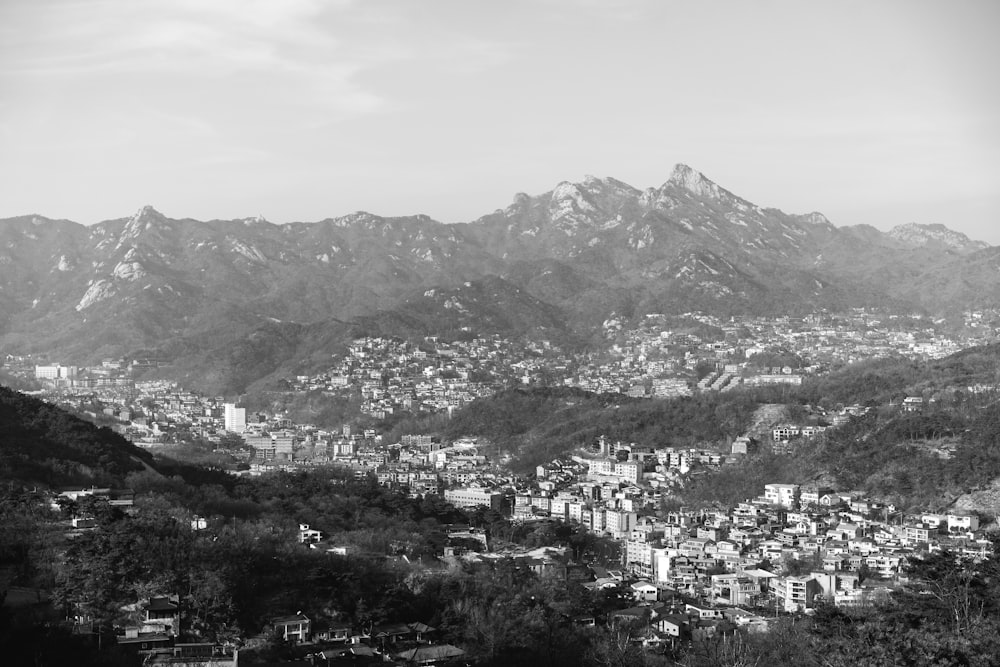 grayscale photo of city near mountain