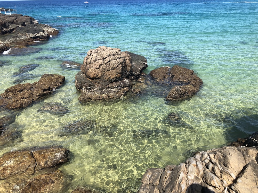 brown rock formation on body of water during daytime