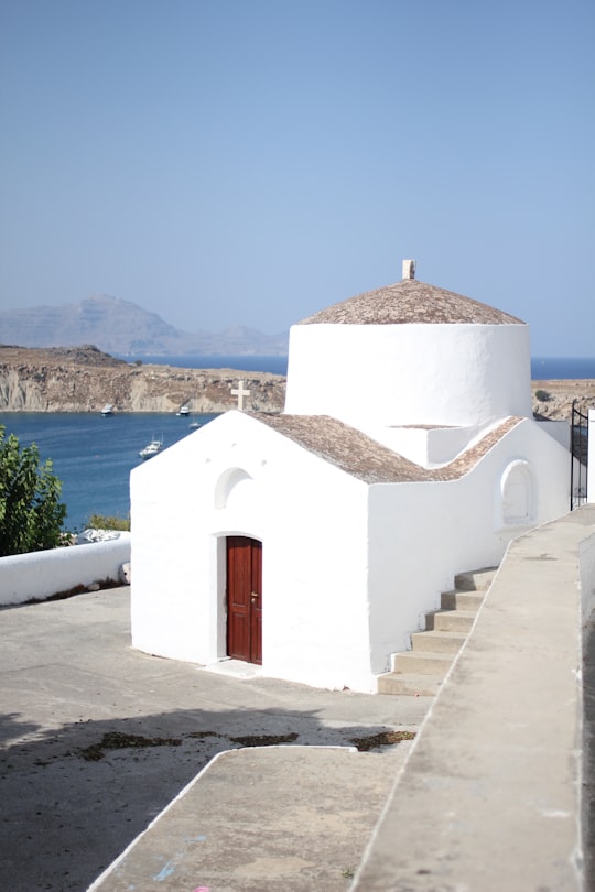 white and brown concrete building near body of water during daytime in Lindos Acropolis Greece