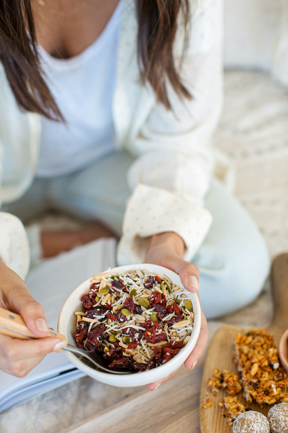 woman in white long sleeve shirt holding white ceramic bowl with food
