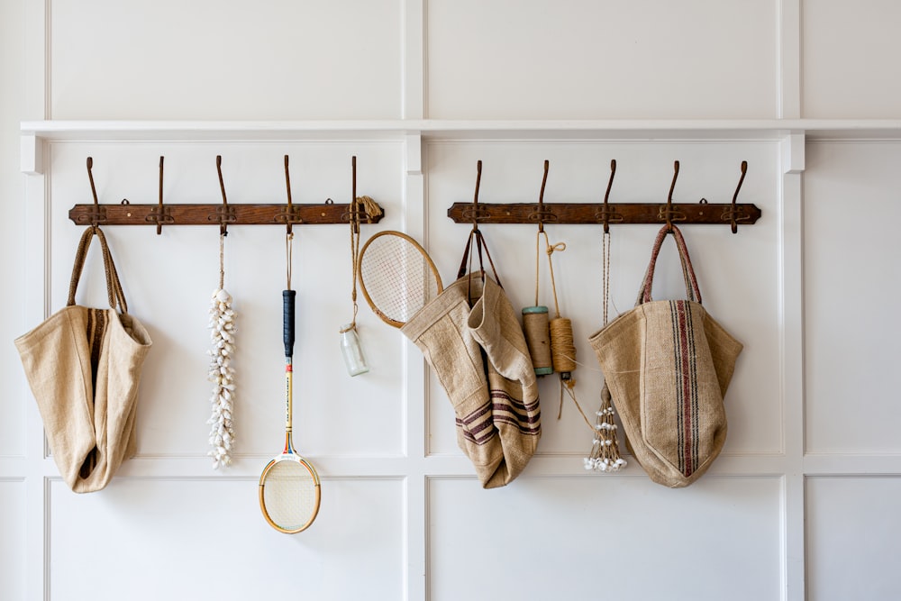 brown and white sling bags hanged on white wooden wall