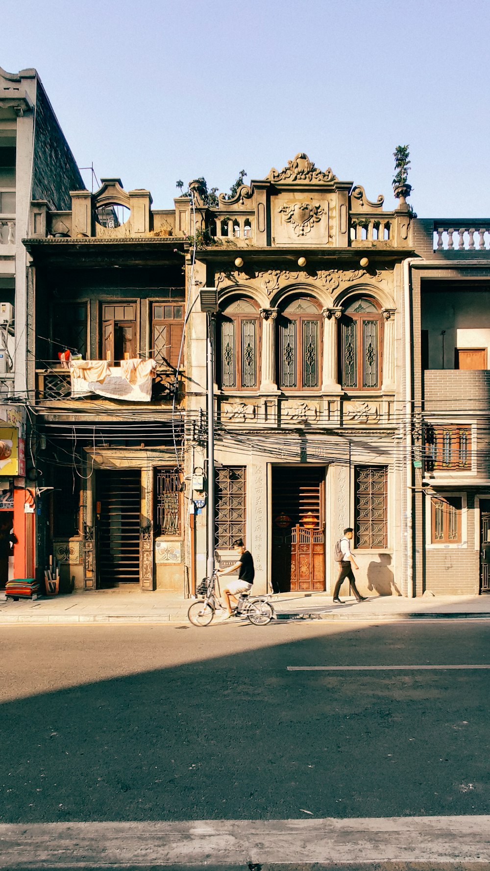 Homme en chemise blanche faisant du vélo près d’un bâtiment en béton brun pendant la journée