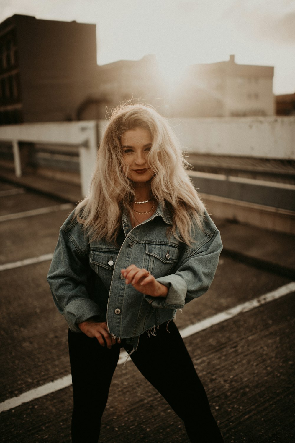 woman in blue denim jacket standing on the sidewalk during daytime