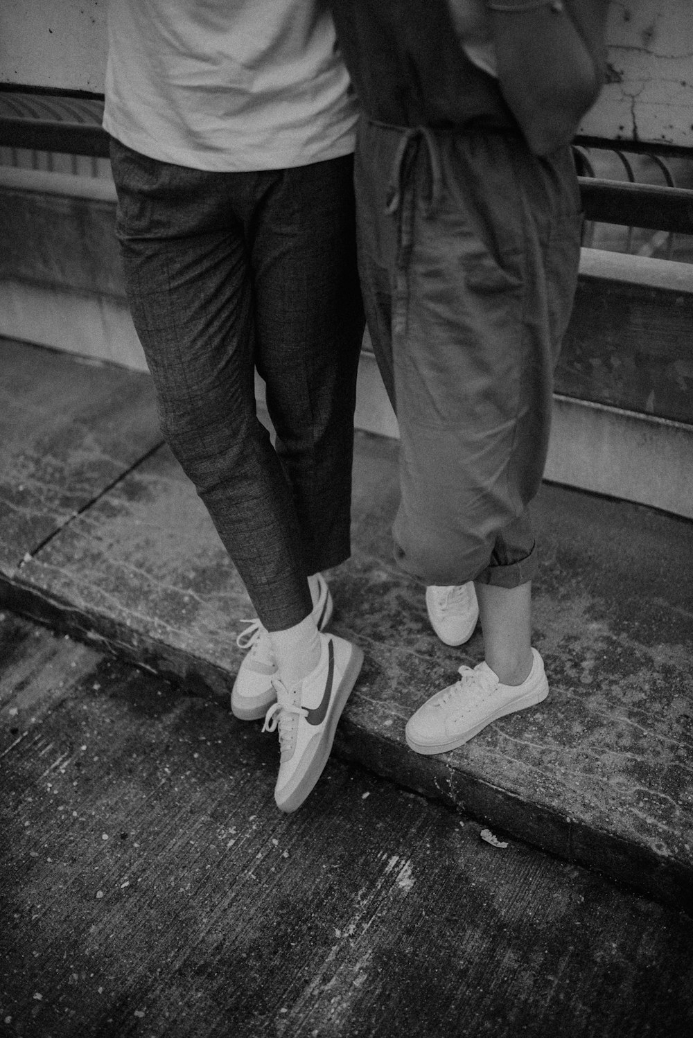 person in black pants and white sneakers standing on concrete floor