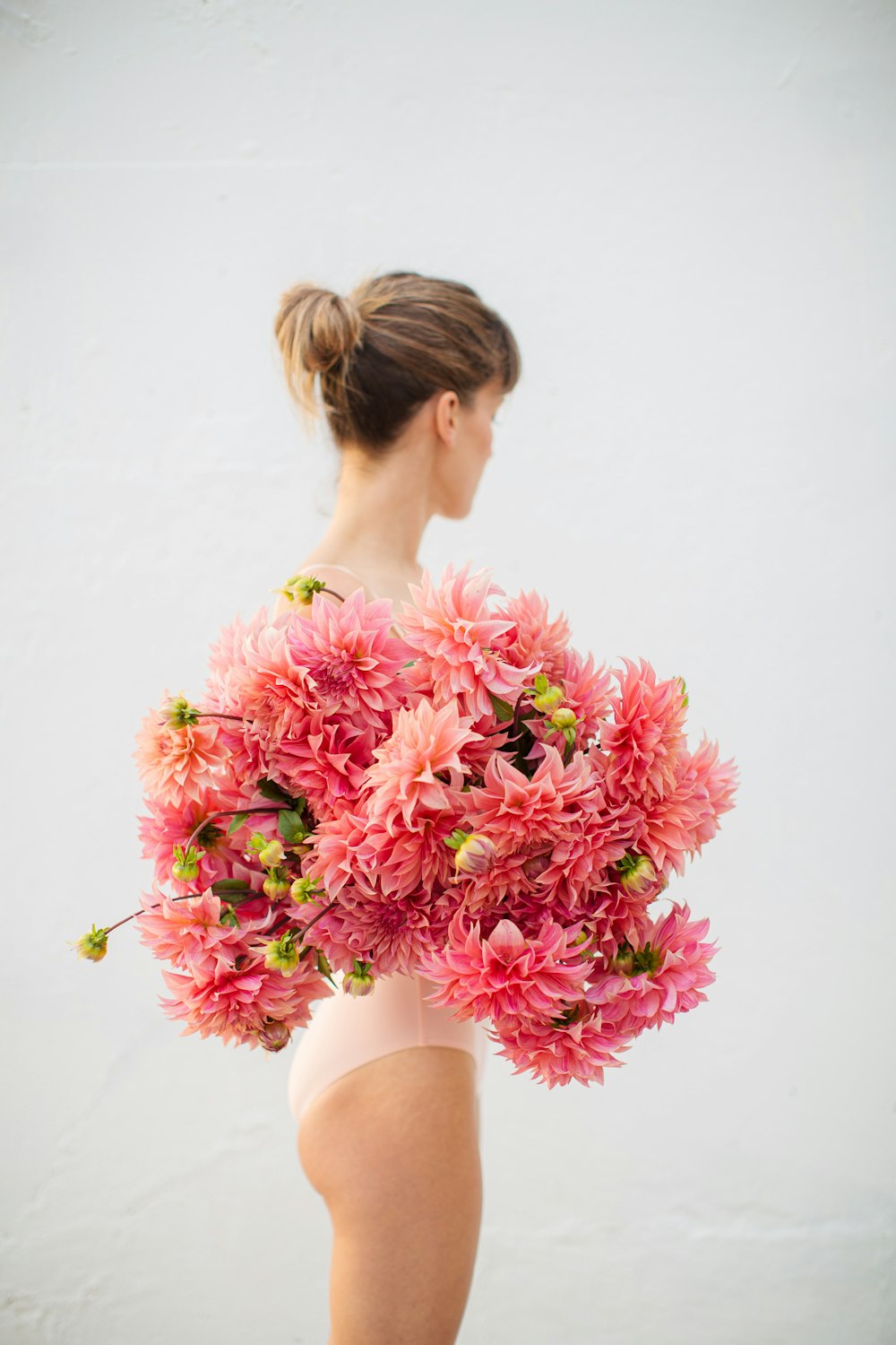 woman in white tank top holding pink flowers