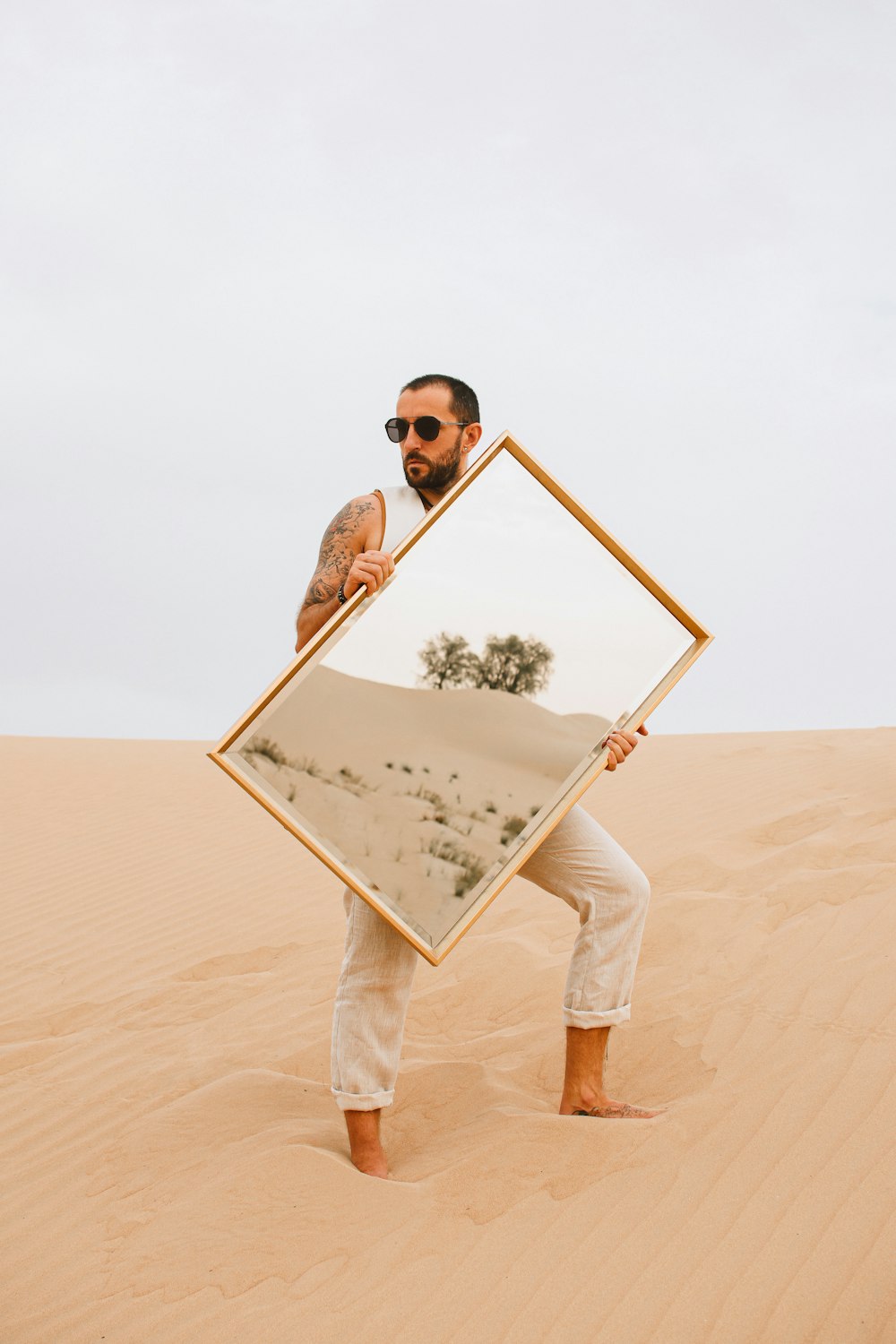 a man holding a picture frame in the desert