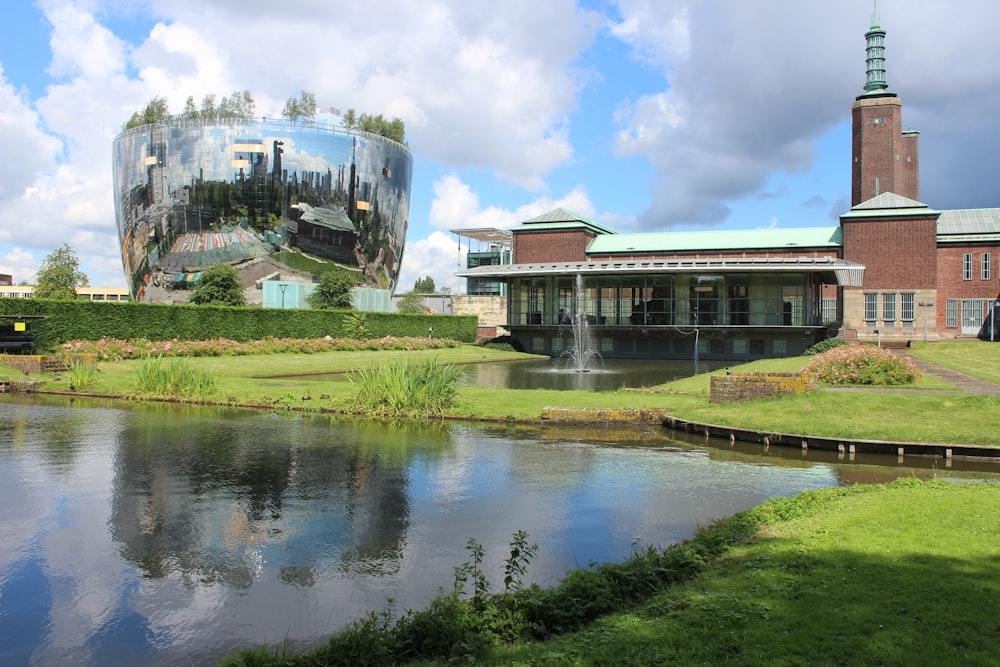 brown concrete building near green grass field and river under white clouds during daytime