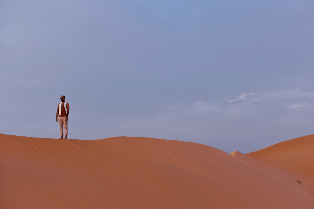 man in white shirt standing on brown sand during daytime