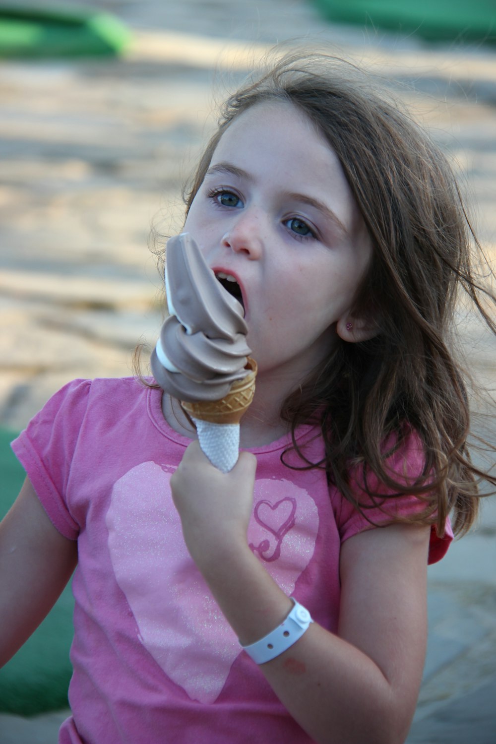 menina na camiseta cor-de-rosa segurando o cone do sorvete